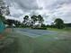 A fenced-in tennis court is ready for play, with trees and landscaping at 14025 Fairway Island Dr # 335, Orlando, FL 32837
