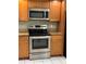 Stainless steel stove and microwave are complimented by warm wood cabinetry and granite countertops at 14844 Laguna Beach Cir, Orlando, FL 32824