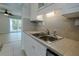 The kitchen features sleek cabinets, tile backsplash, stainless sink, and views of the living area and balcony at 151 N Orlando Ave # 204, Winter Park, FL 32789