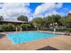 Outdoor swimming pool with clear blue water, surrounded by greenery and a shaded lounging area at 1630 Common Way Rd # 203, Orlando, FL 32814