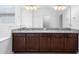 Bathroom vanity with granite counters, double sinks, and dark wood cabinets beneath a large mirror and bright lighting at 17199 Hickory Wind Dr, Clermont, FL 34711