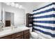 Well-lit bathroom featuring a vanity, mirror, and a shower with a blue-and-white striped curtain at 17199 Hickory Wind Dr, Clermont, FL 34711