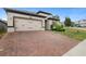 Red brick driveway of a single-story home with a two-car garage at 17199 Hickory Wind Dr, Clermont, FL 34711
