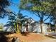 Single-story home with a well-maintained front yard, palm trees, mature trees, and attached garage, featuring a red front door at 17517 Silver Creek Ct, Clermont, FL 34714