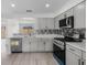 Modern kitchen with stainless steel appliances, light gray cabinets, and tiled backsplash, with a view to another room at 1816 Haperon St, Apopka, FL 32703