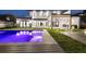 Backyard pool at dusk with outdoor kitchen and travertine pavers at 182 N Phelps Ave, Winter Park, FL 32789