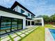 Backyard view highlighting the pool, manicured lawn, and sleek, modern home design at 182 N Phelps Ave, Winter Park, FL 32789