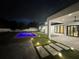 Night view of the backyard featuring a glowing pool, covered patio, and landscaped lighting at 182 N Phelps Ave, Winter Park, FL 32789