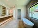 Luxurious bathroom with dual sinks, a soaking tub, decorative accent wall, and a large, bright window at 182 N Phelps Ave, Winter Park, FL 32789