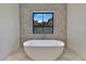 A luxurious freestanding tub is set against a stone accent wall in this modern bathroom at 182 N Phelps Ave, Winter Park, FL 32789