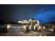 Exterior night view of a modern home with well-lit facade, three-car garage and manicured landscaping at 182 N Phelps Ave, Winter Park, FL 32789