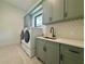 Well-lit laundry room with modern appliances, sink, stylish tile backsplash, and ample cabinet space at 182 N Phelps Ave, Winter Park, FL 32789