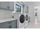 Bright laundry room with front-load washer, dryer, gray cabinets, and quartz countertops at 182 N Phelps Ave, Winter Park, FL 32789