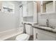 Bathroom featuring a shower-tub combo, granite countertop vanity, and storage shelving above the toilet at 233 E Church Ave, Longwood, FL 32750