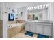 Bright bathroom featuring a soaking tub with tile surround and gray vanity with granite countertop at 3310 Stonewyck St, Orlando, FL 32824