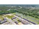 Aerial view of new townhomes with a community pond, green space, and a backdrop of lush trees and a distant highway at 4353 Campsite Loop, Orlando, FL 32824