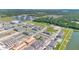 An aerial view of a community showcasing townhomes, a pond, green spaces, and amenities buildings amidst a growing development at 4353 Campsite Loop, Orlando, FL 32824