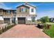 Two-story townhome features a stone facade, brick driveway, and attached garage, exuding curb appeal at 4353 Campsite Loop, Orlando, FL 32824