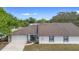 Single-story home featuring a two-car garage, neutral paint, well-maintained front yard, and lush surrounding trees at 4636 Fern Pine Dr, Orlando, FL 32808