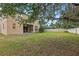 Home's backyard featuring a large lawn and mature trees with a glimpse of a covered pool area at 5525 Oakworth Pl, Sanford, FL 32773