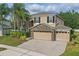 Attractive two-story home featuring stone details, a three-car garage, and a well-maintained front yard with palm trees at 5525 Oakworth Pl, Sanford, FL 32773