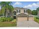 Charming two-story home featuring stone accents, a three-car garage, and a well-manicured lawn with palm trees at 5525 Oakworth Pl, Sanford, FL 32773