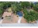 Aerial view of houses on a street with lush green trees; one has a pool, and another has a red patio umbrella at 6345 Hatcher Rd, Lakeland, FL 33811