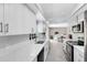 Bright kitchen features white cabinets, quartz countertops, stainless steel appliances, and wood-look tile flooring at 7741 Pine Hollow Ct, Orlando, FL 32822