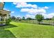 Home's backyard featuring manicured lawn, black fence, mature trees, and beautiful golf course at 8150 Prestbury Dr, Orlando, FL 32832