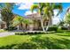 Charming two-story home showcasing a lush lawn, mature palm trees, and an attached two-car garage at 8150 Prestbury Dr, Orlando, FL 32832