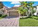 Charming two-story home featuring a lush lawn, mature palm trees, brick paver driveway, and an attached two-car garage at 8150 Prestbury Dr, Orlando, FL 32832