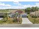 Aerial view of a light-blue home with a large front yard and an extended driveway leading to a two-car garage at 10 Alicante Ct, Kissimmee, FL 34758
