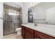 Bathroom featuring tiled shower, white countertop on dark cabinets, and a large mirror at 11255 Se 170Th Pl, Summerfield, FL 34491