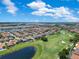 An aerial view of residences overlooking lush golf course with a tranquil pond under a blue sky at 13139 Stanthorne Ave, Orlando, FL 32832