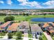 An aerial view showcases a neighborhood, golf course, and lake under a partly cloudy blue sky at 13139 Stanthorne Ave, Orlando, FL 32832