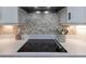 Modern kitchen cooktop area showcasing granite countertops, stylish backsplash, and sleek black cooktop at 13139 Stanthorne Ave, Orlando, FL 32832