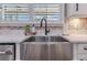Close-up of a stainless steel farmhouse kitchen sink with white granite countertops and a stylish backsplash at 13139 Stanthorne Ave, Orlando, FL 32832