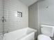 Bathroom featuring a tiled tub, shower with glass door, toilet, and tiled wall niche at 1414 Beaver Pl, Orlando, FL 32806