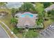 Aerial view of a community pool and clubhouse surrounded by palm trees and green landscaping near a parking lot at 14820 Laguna Beach Cir, Orlando, FL 32824