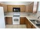 Well-equipped kitchen featuring wood cabinetry, a white range, and a microwave, providing ample cooking space at 1625 Priory Cir, Winter Garden, FL 34787