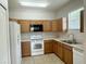 Bright kitchen with wood cabinets, white appliances, and tile flooring, offering functionality and style at 1625 Priory Cir, Winter Garden, FL 34787