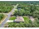 An aerial view showcases a tan-roofed home with a green lawn surrounded by lush trees at 16253 Sw 29Th Court Rd, Ocala, FL 34473