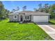 Charming single-story home with a gray exterior, green lawn, and a spacious two-car garage at 16253 Sw 29Th Court Rd, Ocala, FL 34473