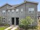 Modern townhome exterior featuring a stone facade, neutral stucco, and flowering tree at 1632 Tropical Palms Circle, Kissimmee, FL 34747