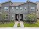 Modern townhome exterior features a black front door and manicured front lawn at 1632 Tropical Palms Circle, Kissimmee, FL 34747