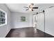 Bright bedroom with dark wood floors, ceiling fan, and sliding barn door at 1701 E Bay St, Winter Garden, FL 34787