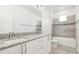 Bright bathroom featuring double sinks, granite countertop, gray tile backsplash and flooring, with a tub-shower combo at 18743 Overton St, Orlando, FL 32833