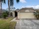 Charming single-story home featuring a two-car garage, neutral stucco, and lush tropical landscaping at 2226 Newt St, Orlando, FL 32837