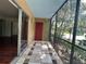 View of the condo's tiled and screened patio, featuring a red door at 2349 Oak Park Way # 107, Orlando, FL 32822