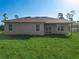Exterior back view of the home with green grass, a covered porch, and mature trees at 2531 Sw 167Th Loop, Ocala, FL 34473